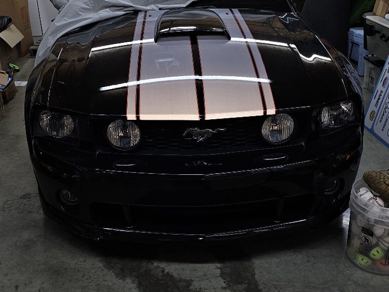 Black coupe with white racing stripes after a refinish in Dallas